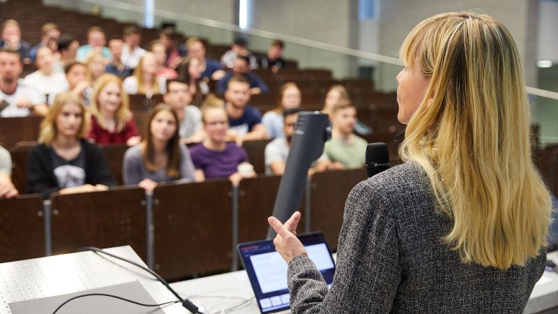 Das Bild zeigt eine Frau, die eine Vorlesung hält