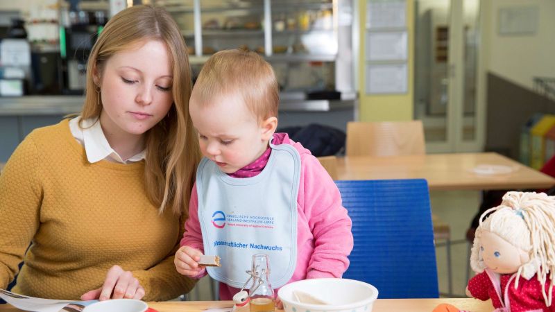 Das Bild zeigt eine junge Frau mit einem Kleinkind beim Lesen